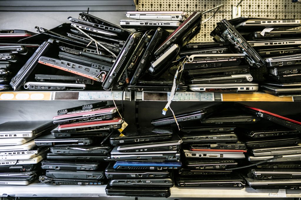 Old laptops stacked on shelves.